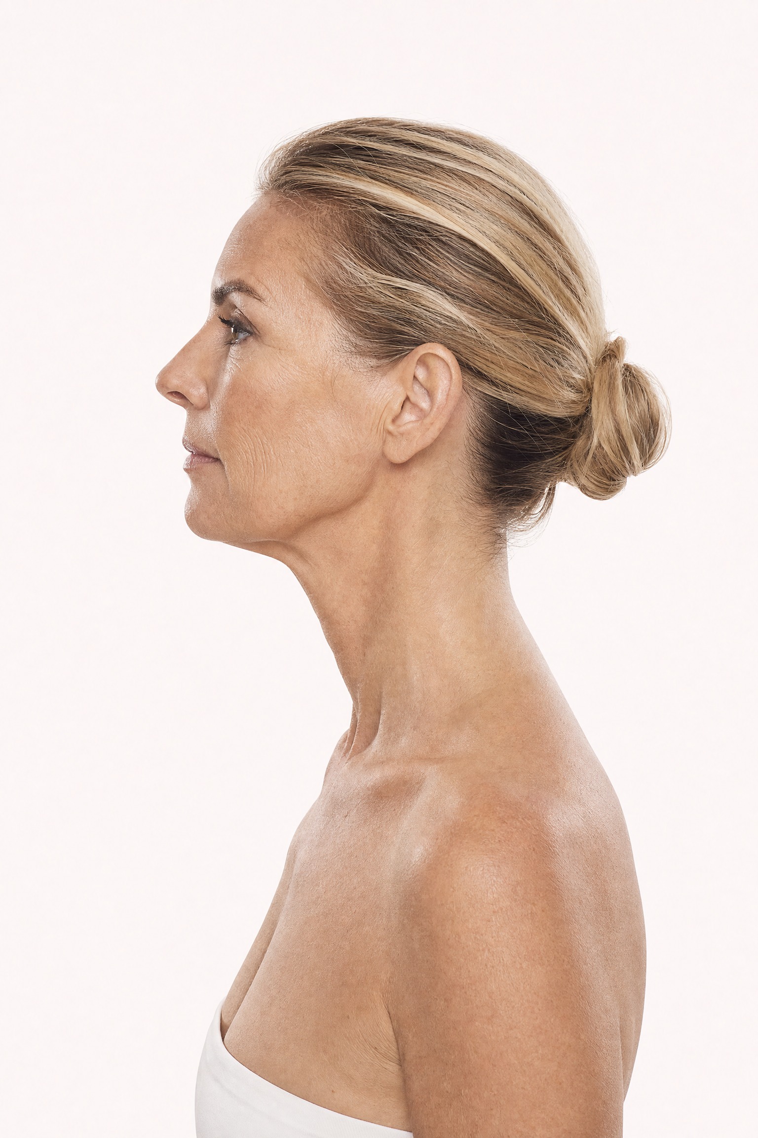 Side profile portrait of a woman in her late 40s showing natural skin laxity along the jawline and neck — the key areas treated for sagging skin at Facial Sculpting London